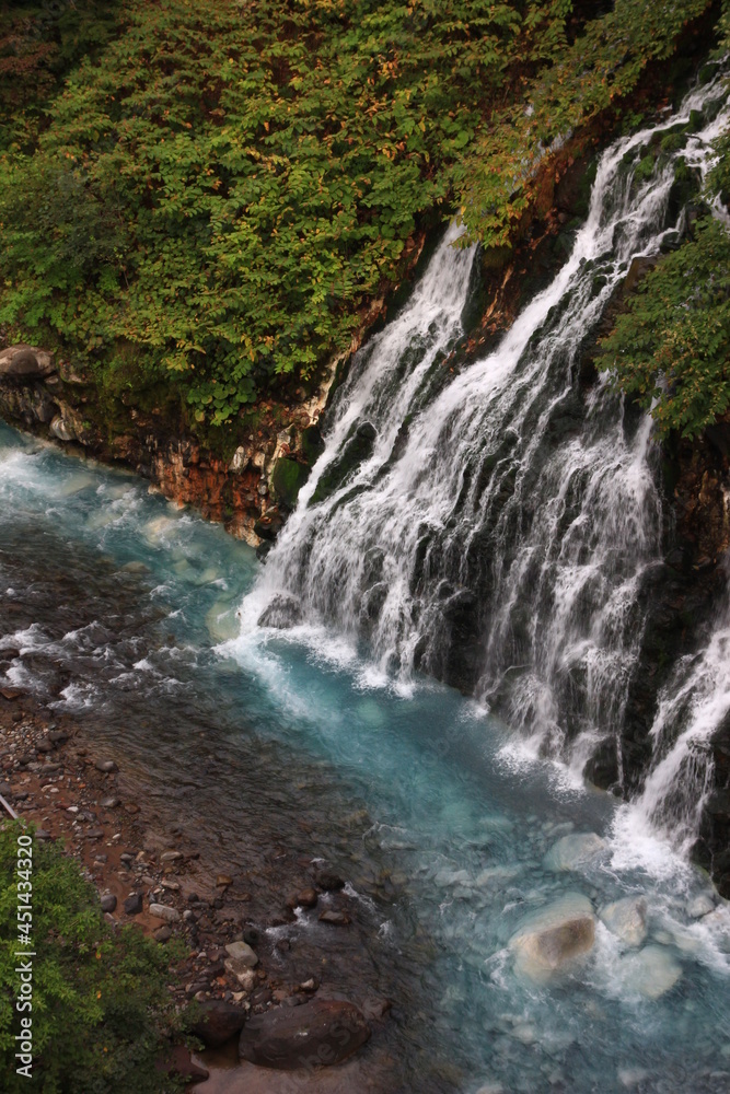 北海道の風景。白髭の滝。滝が流れ落ちる美瑛川は水酸化アルミニウム等の微粒子が光を反射青い。 北海道の風景。白髭の滝。滝が流れ落ちる美瑛川は水酸化アルミニウム等の微粒子が光を反射青い。
