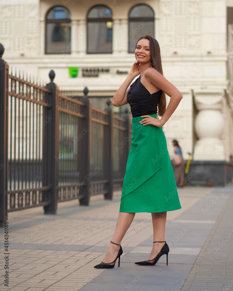 Outdoor portrait of young beautiful pretty caucasian tanned woman wearing stylish clothes. Trendy dressed girl wearing top and green skirt