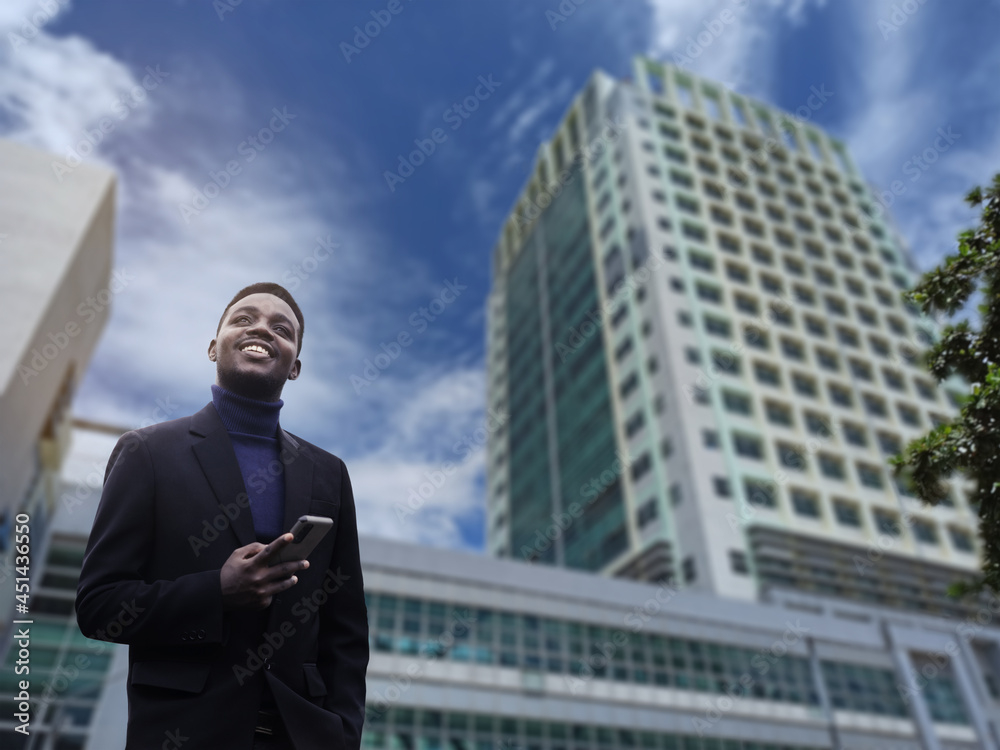 Happy smiling African businessman using smartphone in a suit at a luxurious building hotel Happy smiling African businessman using smartphone in a suit at a luxurious building hotel