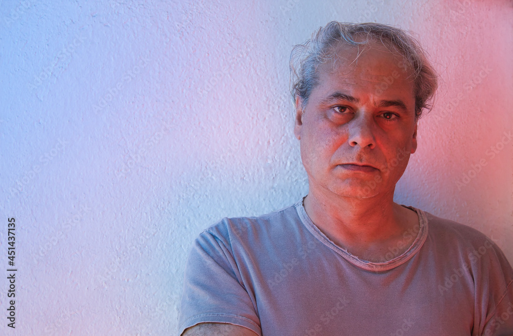 portrait with copy space of mature man with red and blue ambient color lights on a white background looking at camera portrait with copy space of mature man with red and blue ambient color lights on a white background looking at camera