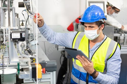 factory worker using tablet computer for finding how to fixing machine control panel in factory