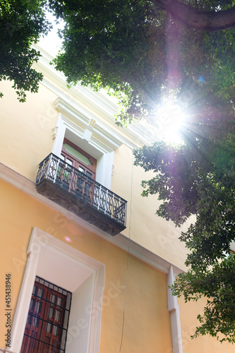 Facade of a building with some yellow tones and a beautiful flash above the trees