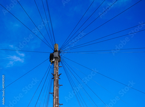 Single telegraph pole with many cables in Leeds, looking up toward blue sky.