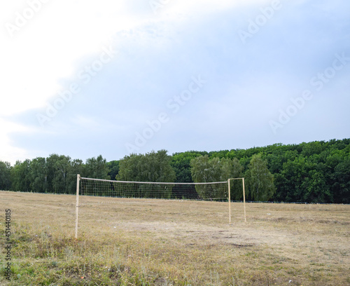 An empty village volleyball court in a clearing on a summer evening