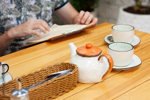 A man in a restaurant reads the menu and drinks tea