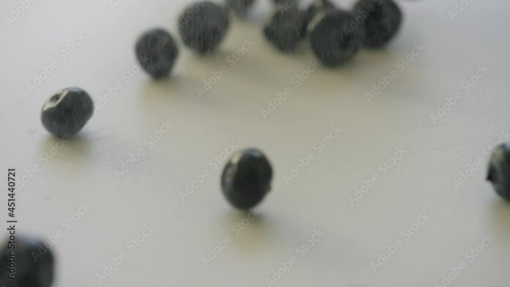 Out of focus motion blur on moving ripe fresh blueberries falling on a white surface with copyspace in the center
