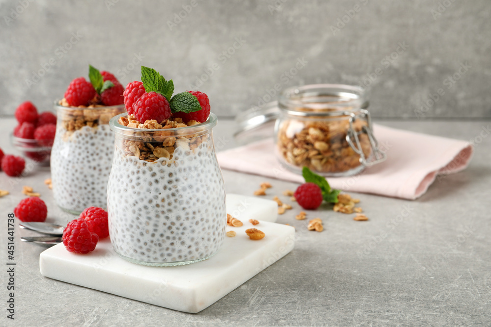 Delicious chia pudding with raspberries and granola on grey table. Space for text Delicious chia pudding with raspberries and granola on grey table. Space for text