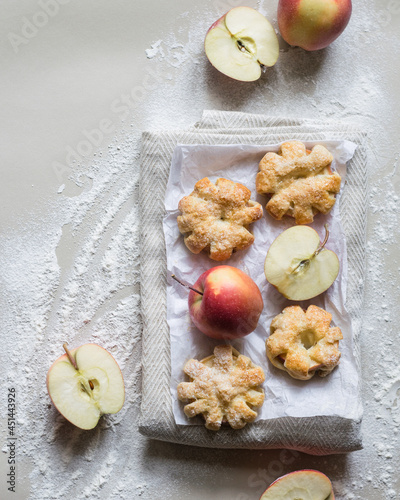 Puff pastry apple pastry turnovers with ripe apples on white paper, top view
