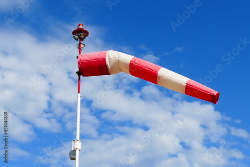 Air sock measuring the wind speed at stormy weather. Hurricane, tornado and storm concept. An red wind indicator blowing on a hospital helicopter landing field, Neustadt am Rübenberge. photo