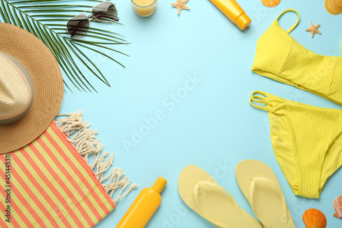 Frame made with different beach objects on light blue background, flat lay. Space for text
