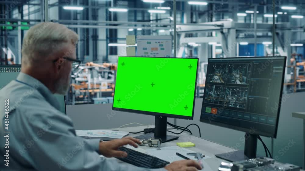 Car Factory Monitoring Office: Male Chief Automotive Engineer Sitting at the Desk Working on Green Screen Chroma Key Computer. Automated Robot Arm Assembly Line Manufacturing Vehicles Car Factory Monitoring Office: Male Chief Automotive Engineer Sitting at the Desk Working on Green Screen Chroma Key Computer. Automated Robot Arm Assembly Line Manufacturing Vehicles