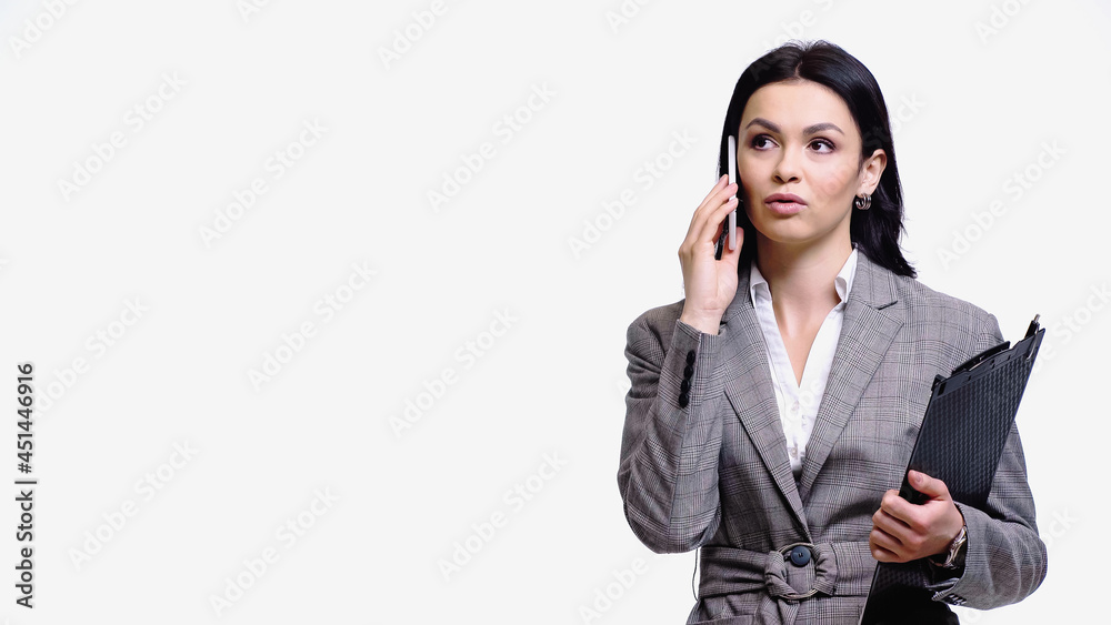 Young businesswoman talking on mobile phone while holding clipboard isolated on white. Young businesswoman talking on mobile phone while holding clipboard isolated on white.