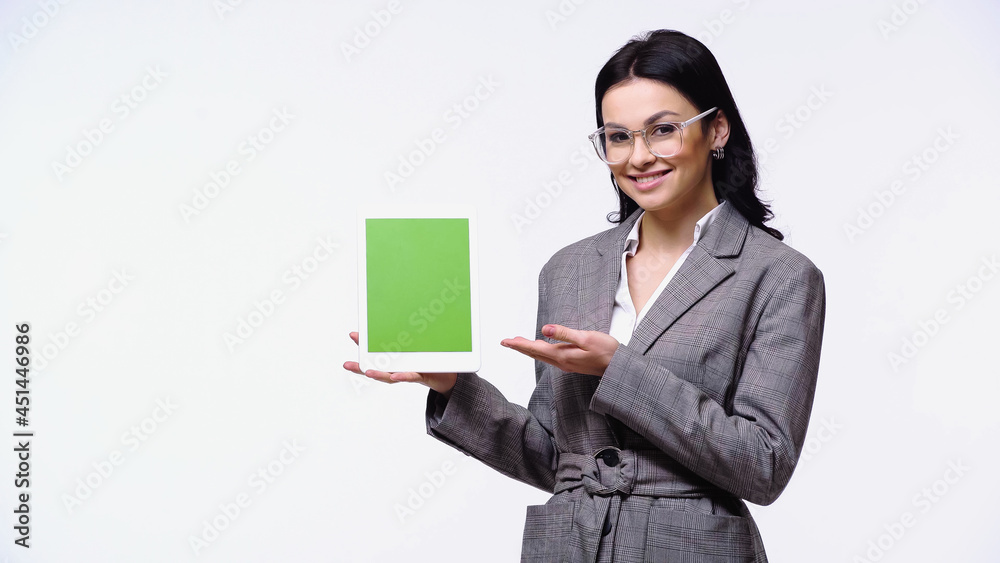 Businesswoman smiling while pointing at digital tablet with green screen isolated on white. Businesswoman smiling while pointing at digital tablet with green screen isolated on white.