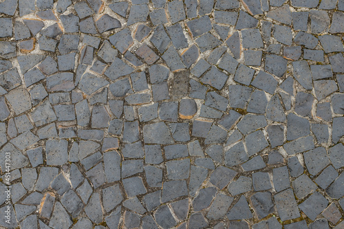 Sidewalk made with Petit-pave (small pavement) which is used in pavements in Brazil. In the image, the sidewalk is made with white stones that are dirty over time and between them dirt and weeds.
