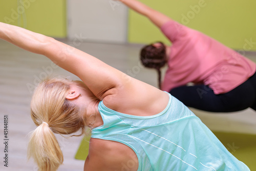 Two girls in sportswear are doing yoga in the hall. Women perform difficult asanas. Calm, balance and concentration concept.
