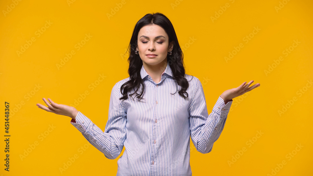 Businesswoman with closed eyes pointing with hands isolated on yellow.