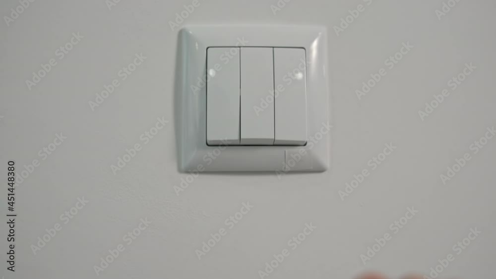 young woman turns on light on switch to illuminate room, close-up young woman turns on light on switch to illuminate room, close-up