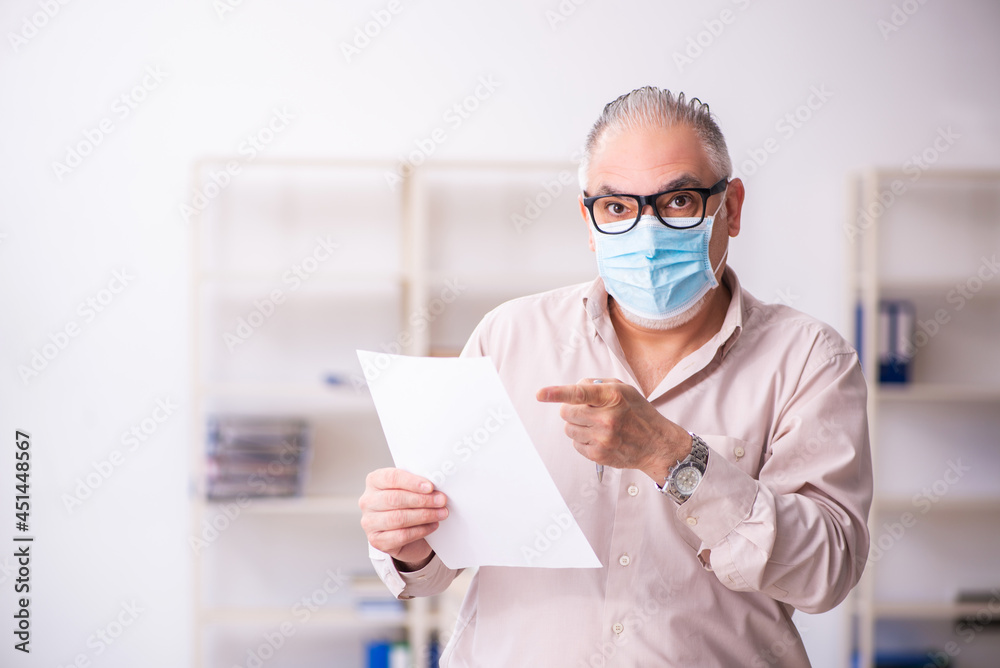 Old male employee working at workplace during pandemic Old male employee working at workplace during pandemic