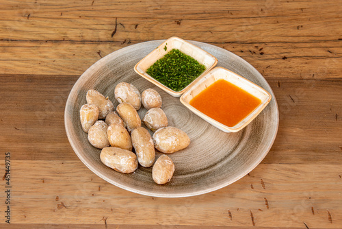 Canarian recipe of wrinkled potatoes with sauces on porcelain plate and wooden table photo