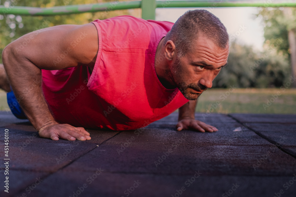 Fototapeta premium handsome muscular man wearing red shirt doing push ups