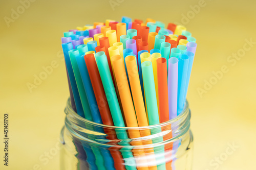 Pile of colorful plastic straws in a glass jar