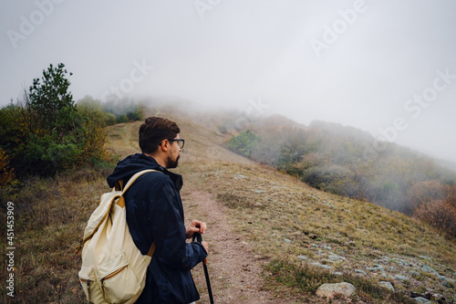 young man traveler in autumn misty nature. rear view. concept active healthy lifestyle, adventure and travel vacation