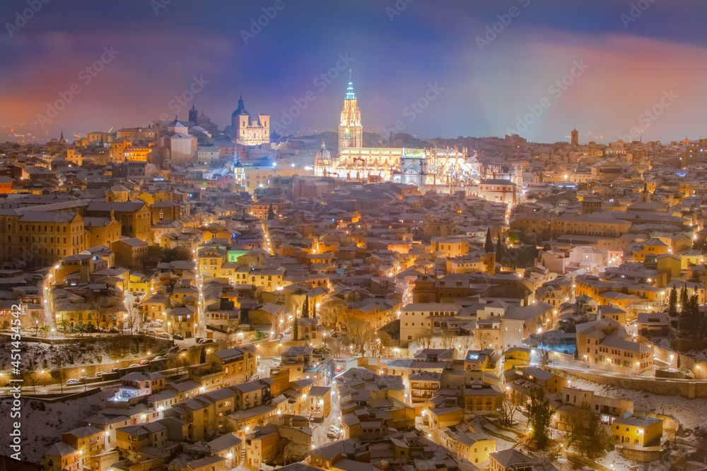 Aerial night view of the skyline of the old snowy European city with the ancient cathedral in a snowy night, Filomena, Toledo, Spain.
