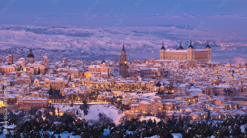 Panoramic aerial view of the skyline of the old snowy European city on a snowy and colorful sunset day, Filomena, Toledo, Spain.