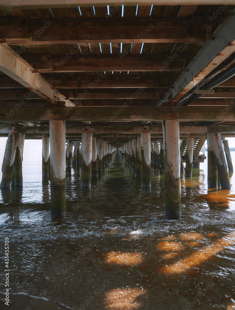 Wooden pier columns standing in the sea. Baltic Sea pier in Poland. Waterfront under the pier made of wood.