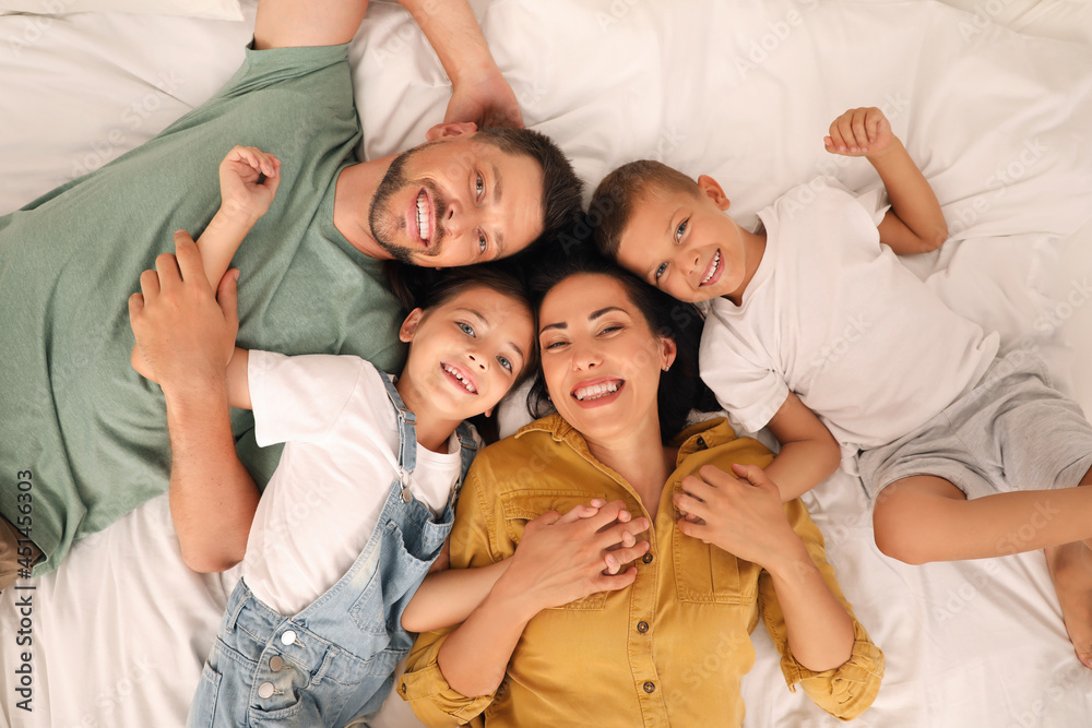 Happy family with children having fun on bed, top view
