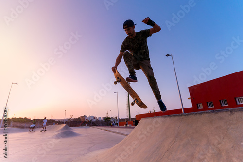 young skateboarder man jumps with his board on the ramp of a skatepark at sunset. movement 1