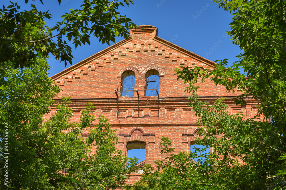 part of a ruined wall with a red brick roof surrounded by greenery