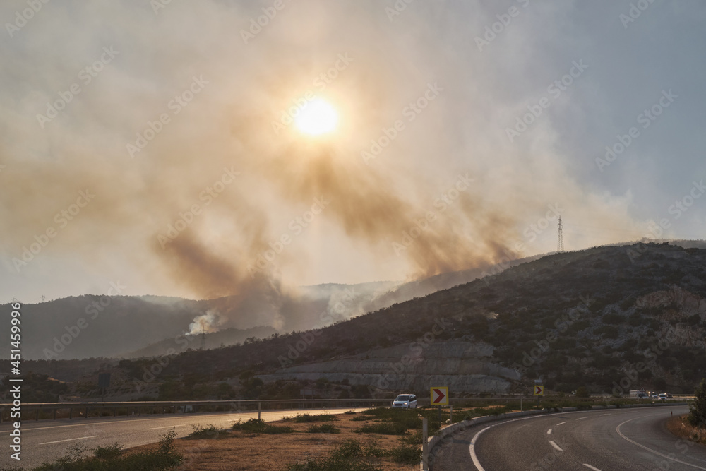 Summer forest fires. Smoke of a forest fire obscures the sun. Road D400 Antalya - Mersin against burning forests. Natural disasters. Bogsak, Mersin province, Turkey. July 29, 2021
