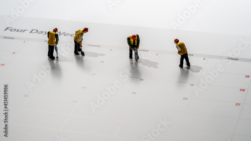 Printed calendar for a 4 day working week showing weekend days in red with small workmen working in the workweek