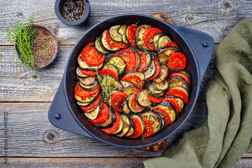 Modern style traditional French ratatouille with tomatoes, eggplant and zucchini served as top view in a rustic cast-iron skillet