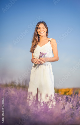 Joyful and happy young beautiful woman in white dress in a lavender field.