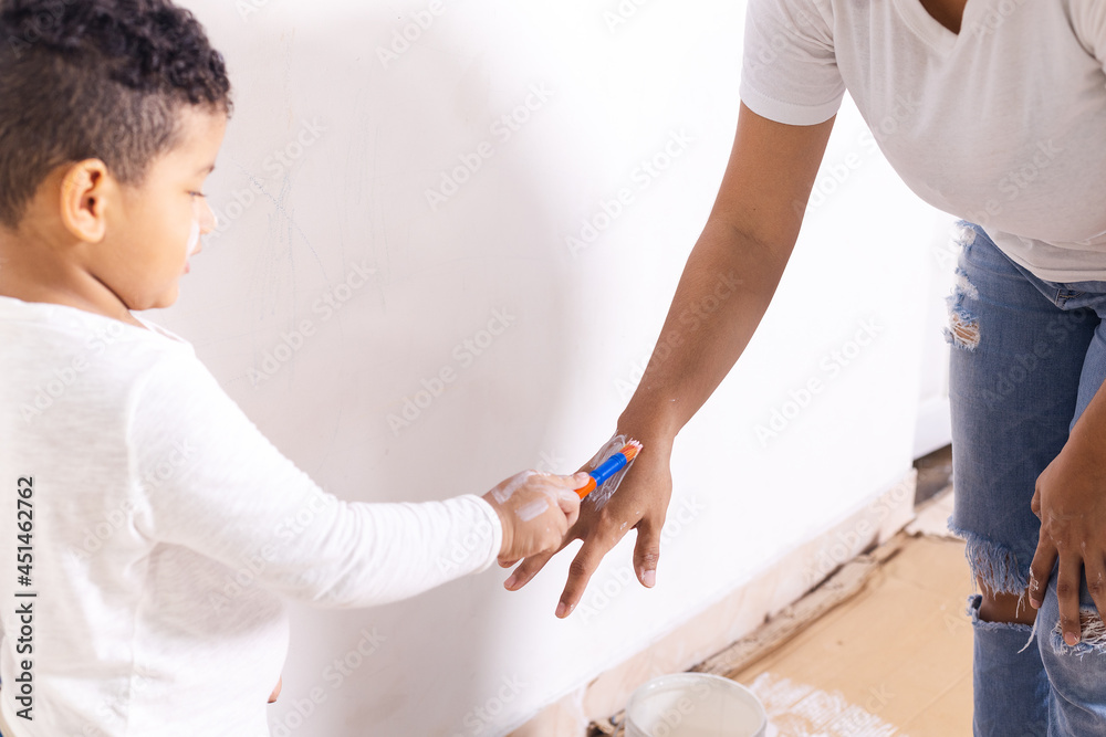 Fototapeta premium Hispanic mom paints the child's hand with white paint