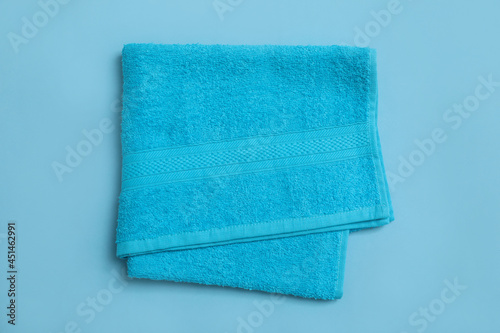 Folded soft beach towel on light blue background, top view