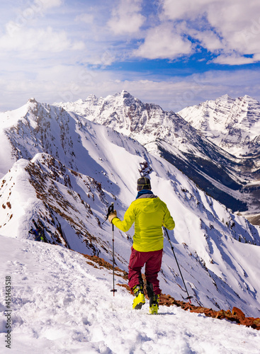 Man Hiking On Summit Mountain Peak In Epic Extreme Winter Landscape