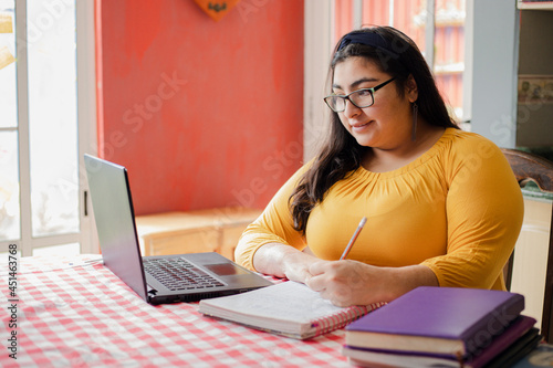 Young hispanic woman studying at home - concentrated college student studying online - woman working from home