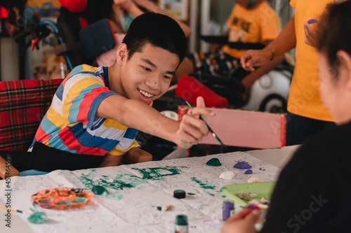Obraz na plátne Handicapped teenager boy on wheelchair with happy face doing art work with friends, Lifestyle of smart disabled kid learning activity in special children school, Mental health classroom concept