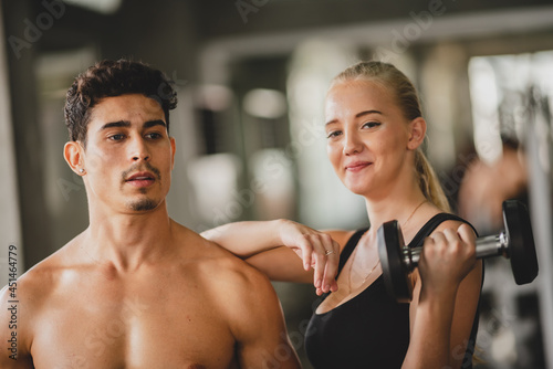 Personal trainer coach helping young woman exercising in the sport gym, training for active workout in fitness, body healthy sport lifestyle