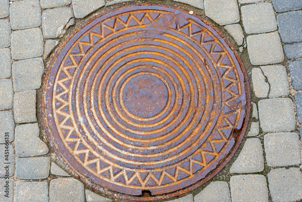 Metallic manhole cover of the city sewerage close-up.