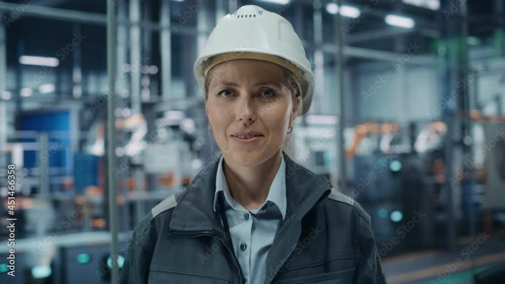 Car Factory Office: Portrait of Female Chief Engineer Wearing Hard Hat Looking at Camera, Smiling. Professional Technician. Automated Robot Arm Assembly Line Manufacturing High-Tech Electric Vehicles Car Factory Office: Portrait of Female Chief Engineer Wearing Hard Hat Looking at Camera, Smiling. Professional Technician. Automated Robot Arm Assembly Line Manufacturing High-Tech Electric Vehicles