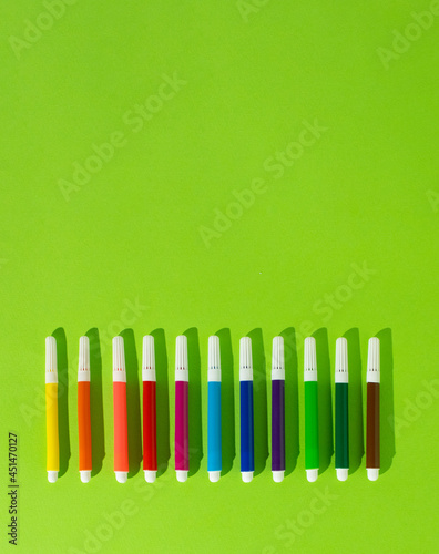 September, back to school, office creative concept on bright green background with rainbow colored felt-tip pens, markers. minimal copy space concept.
