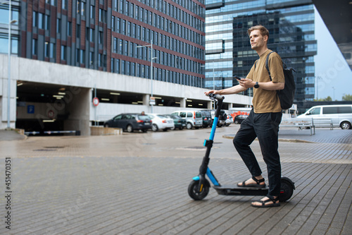 Sustainable mobility city transportation. Green sustainable transportation. Young man unlocks an e-scooter with his mobile phone. Electric scooter new eco way mobility. Climate neutral cities goals.