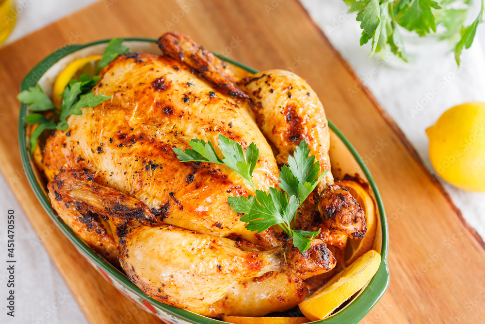 Whole roasted chicken with fresh parsley and lemon wedges in a festive dish Whole roasted chicken with fresh parsley and lemon wedges in a festive dish