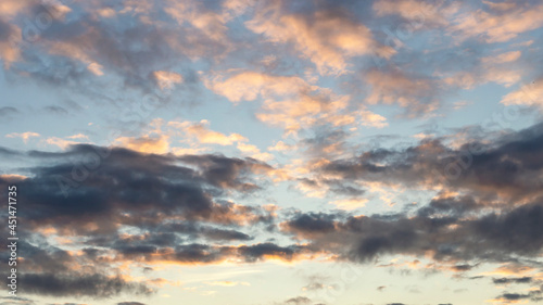 Blue sky with large dark cumulus clouds illuminated by the evening setting sun as a natural background