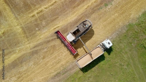 Aerial drone view. Overloading grain from combine harvesters into grain truck in field. Harvester unloder pouring harvested wheat into a box body. Agriculture, harvesting season. photo