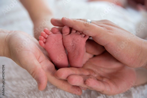 the baby's small legs are gently held in the parent's hands